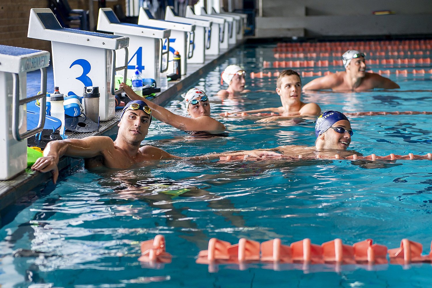 Squad swimmers resting at the pool wall